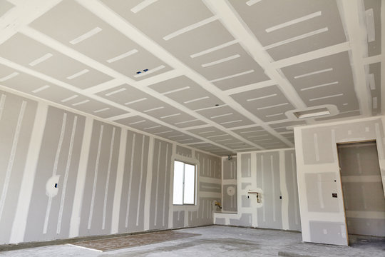 Drywall taping and mudding in a room with ceiling joints